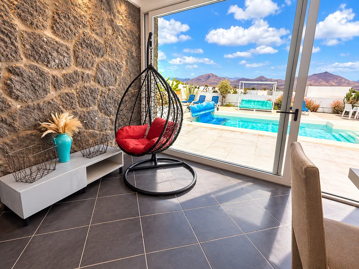 Hanging chair by the stone wall and the sliding door to the pool
