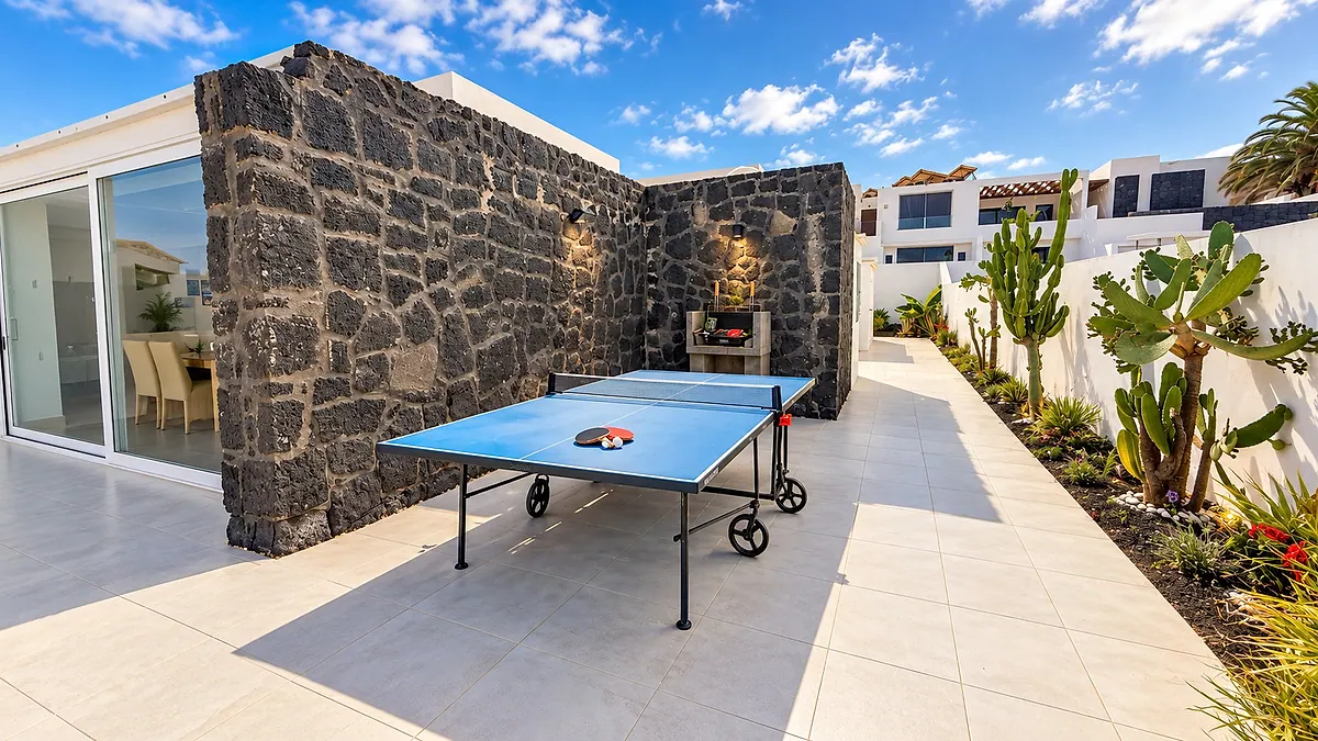 Side patio with a ping pong table and barbecue beside a volcanic stone wall
