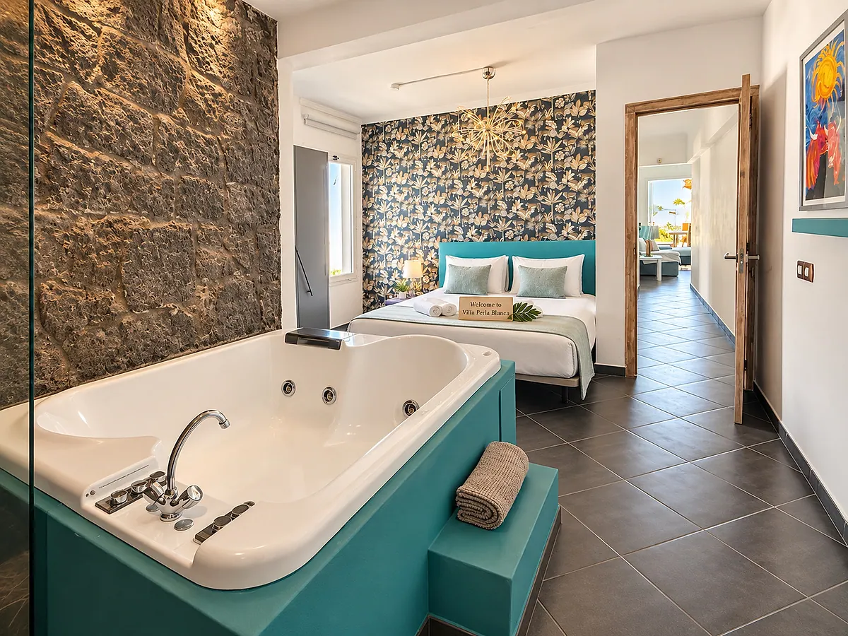 Bedroom with a volcanic stone wall, turquoise headboard and hydromassage bathtub