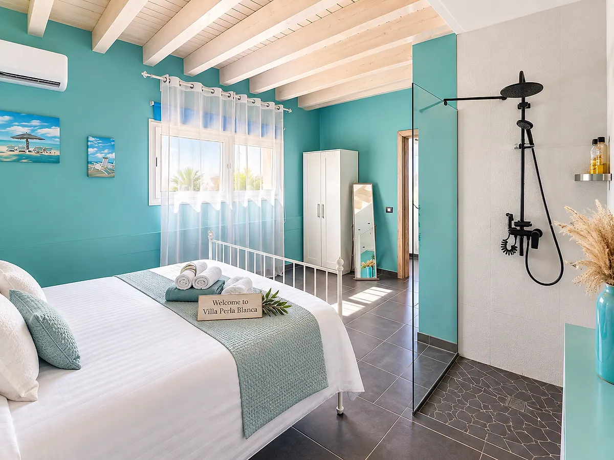 Turquoise bedroom with a double bed, white beamed ceiling and glass shower